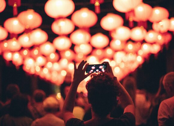 kobieta trzymająca telefon robi zdjęcie instalacji złożonej ze świecących lampionów | China Town | 11. Bella Skyway Festival