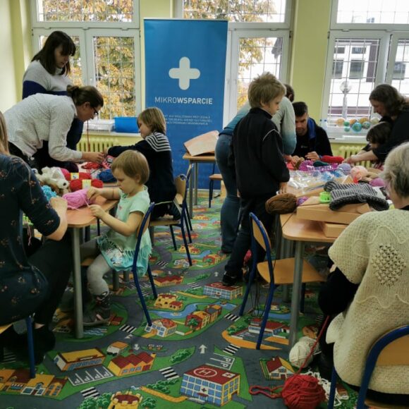 dzieci i dorośli siedzacy przy stołach podczas zajęć