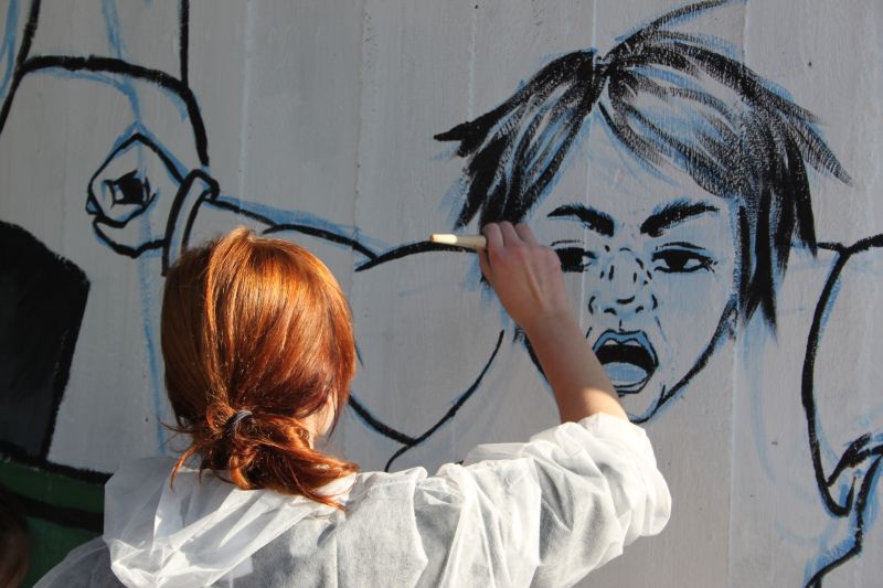 dziewczyna malująca postać na murze
