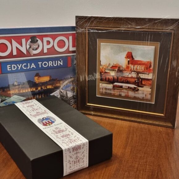 Gra Monopoly, zdjęcie panoramy Torunia w ramce oraz pudełkio z kawą na stole