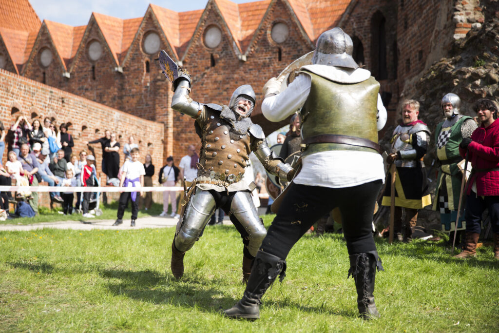 Walka dwóch rycerzy w zbrojach na tle zamku